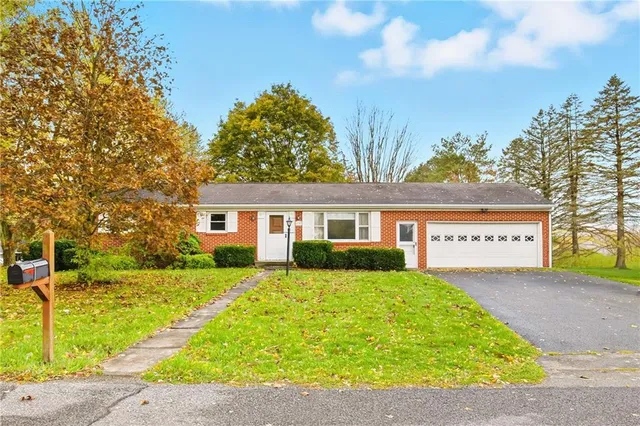 a front view of a house with a yard and trees