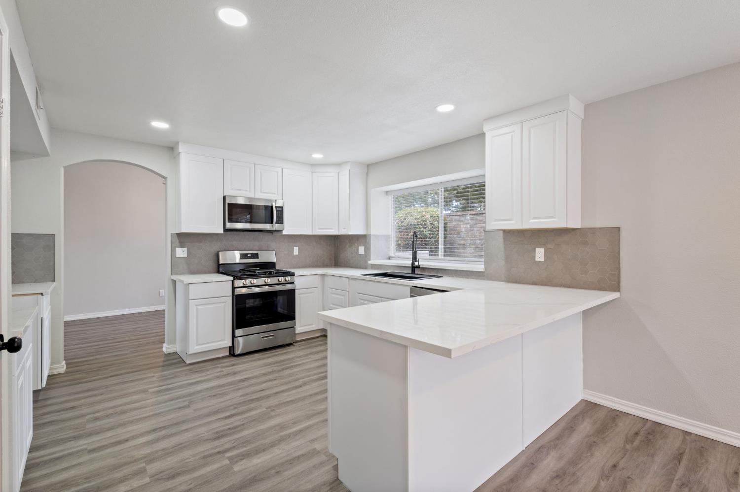 7300 Saltgrass Way Elk Grove, CA 95758 - Photo 11 of 35 a kitchen with a sink a stove a microwave a center island and a window