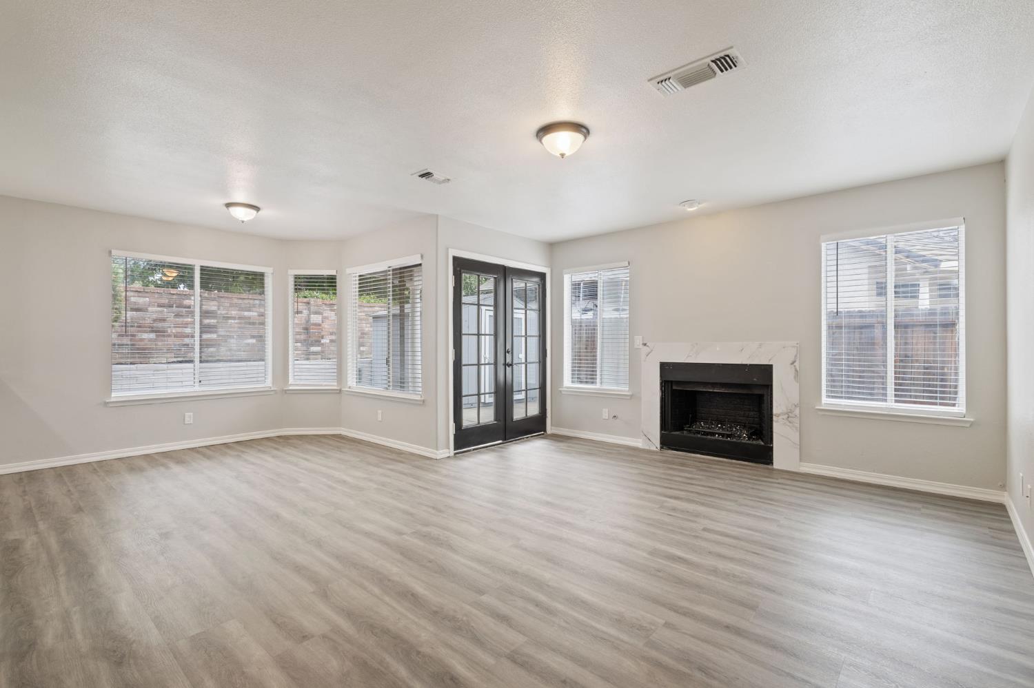 7300 Saltgrass Way Elk Grove, CA 95758 - Photo 17 of 35 an empty room with windows fireplace and wooden floor