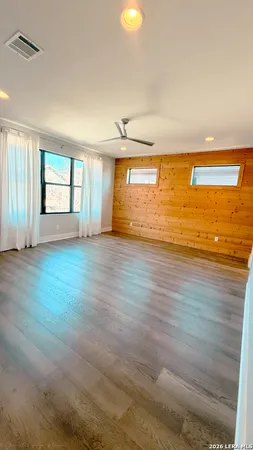 an empty room with wooden floor and windows
