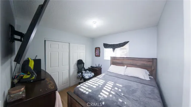 a bedroom with a bed and a flat tv screen on the dresser