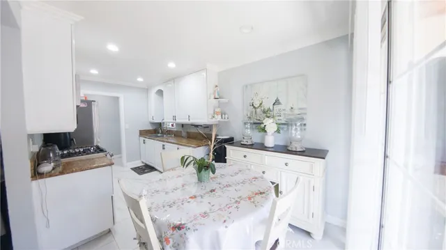 a kitchen with stainless steel appliances kitchen island granite countertop a stove a sink a refrigerator and white cabinets with wooden floor