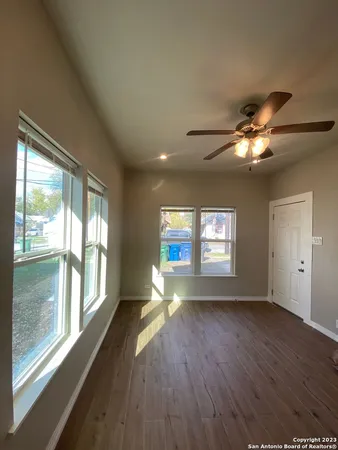 a view of empty room with wooden floor and fan