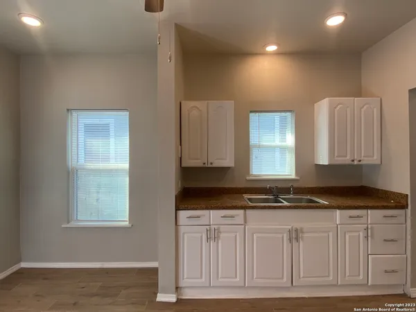 a kitchen with granite countertop white cabinets and sink
