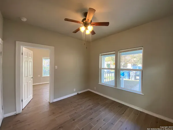a view of an empty room with wooden floor and a window
