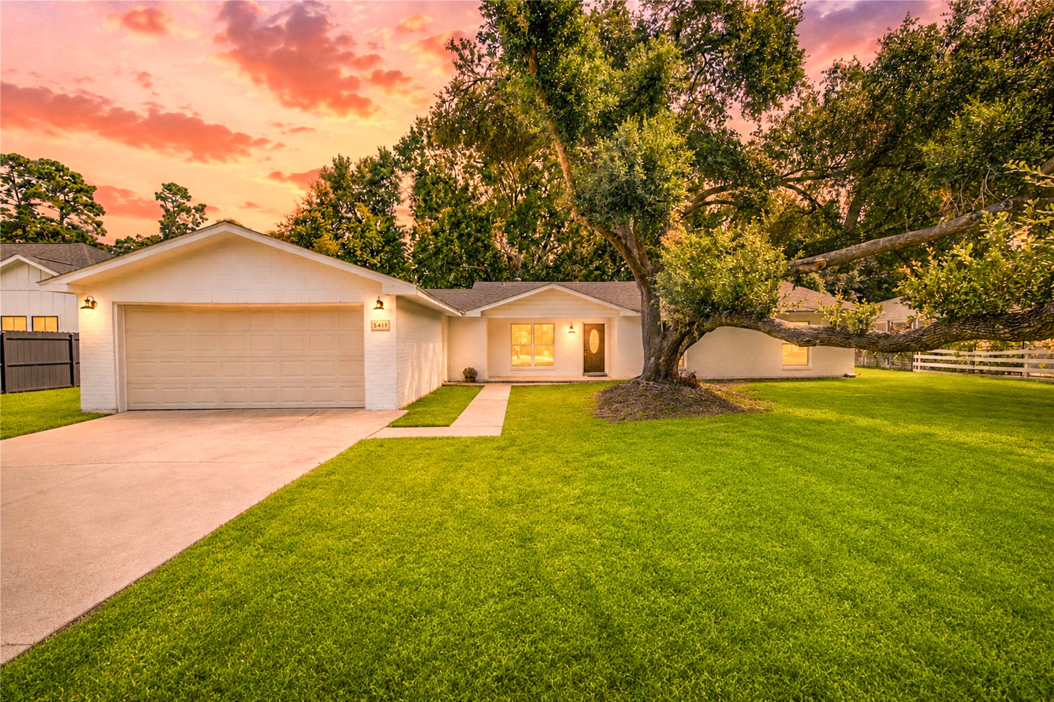 5411 Logston Lane Spring, TX 77389 - Photo 5 of 50 Charming ranch-style home with a spacious front yard and mature trees, set against a stunning sunset backdrop.
