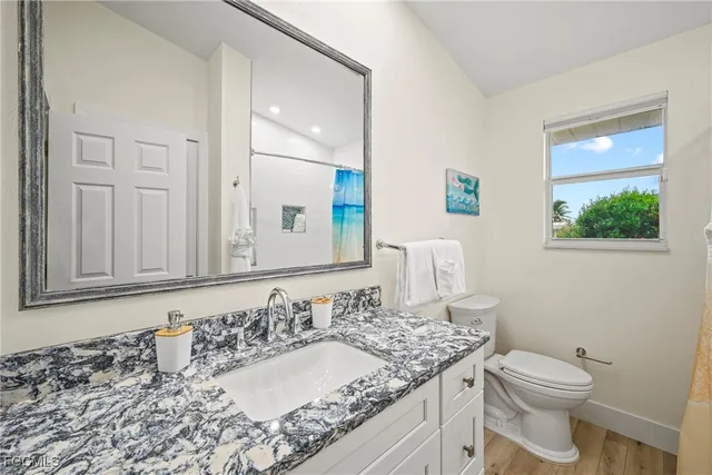 a bathroom with a granite countertop sink and a toilet