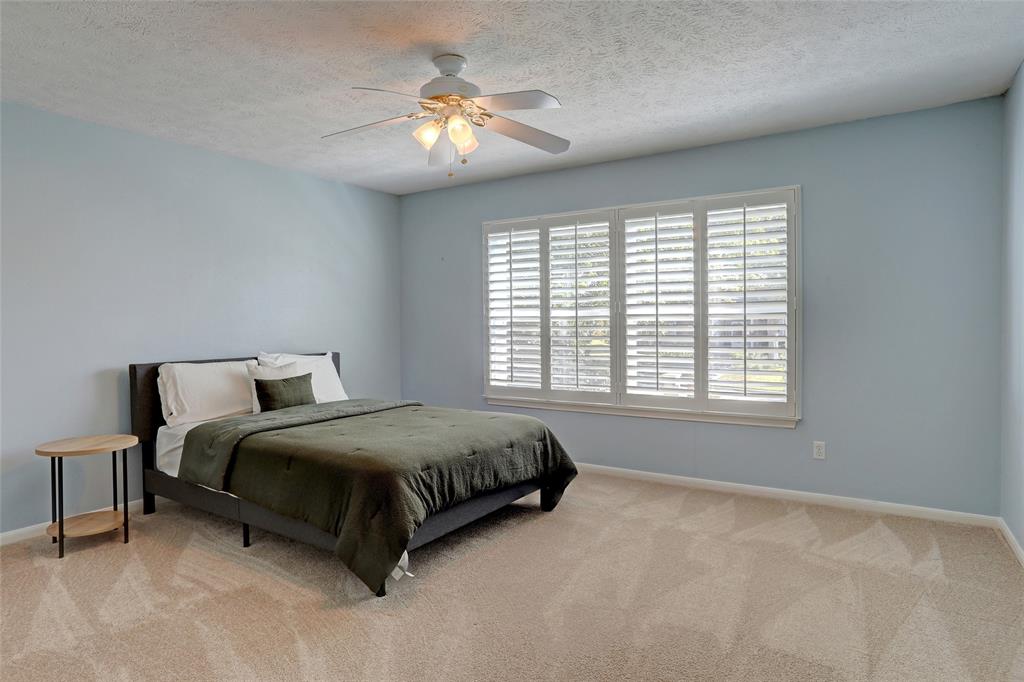 2905 Wyndham Lane Richardson, TX 75082 - Photo 20 of 27 a spacious bedroom with a bed and a chandelier