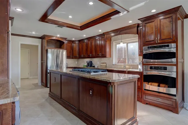 a kitchen with kitchen island granite countertop stainless steel appliances cabinets a sink and a counter top space