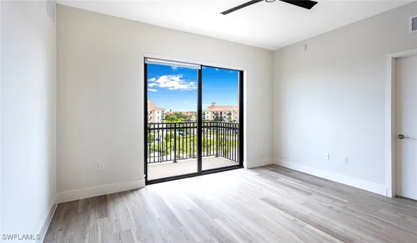 an empty room with wooden floor and balcony