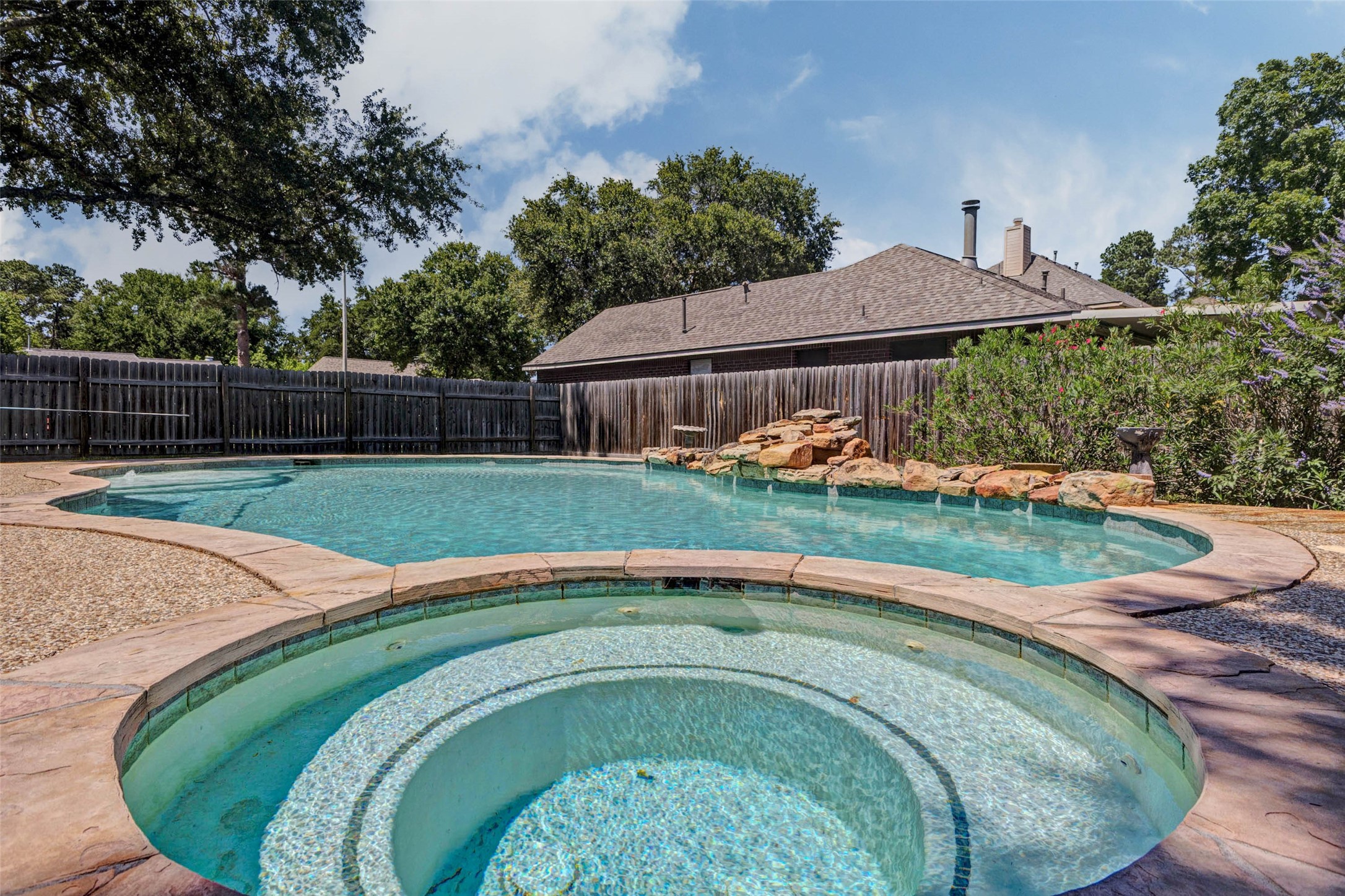 9215 Landry Boulevard Spring, TX 77379 - Photo 39 of 42 Natural stone coping complements the expansive decking and enhances the backyard’s resort style feel, creating a seamless and inviting outdoor retreat around the pool and spa.