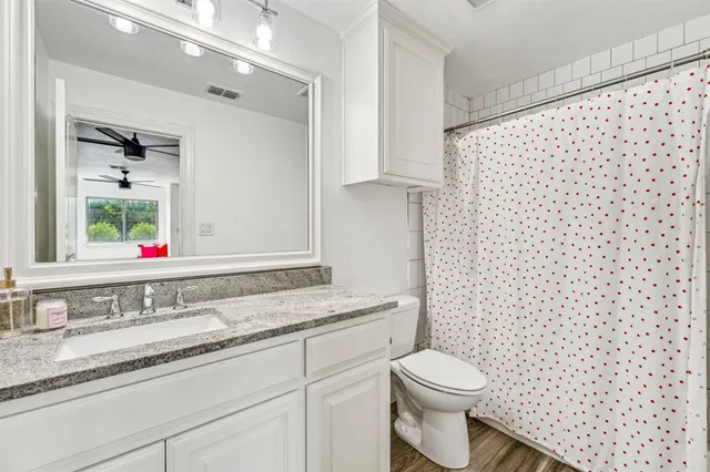 a bathroom with a granite countertop toilet sink and mirror