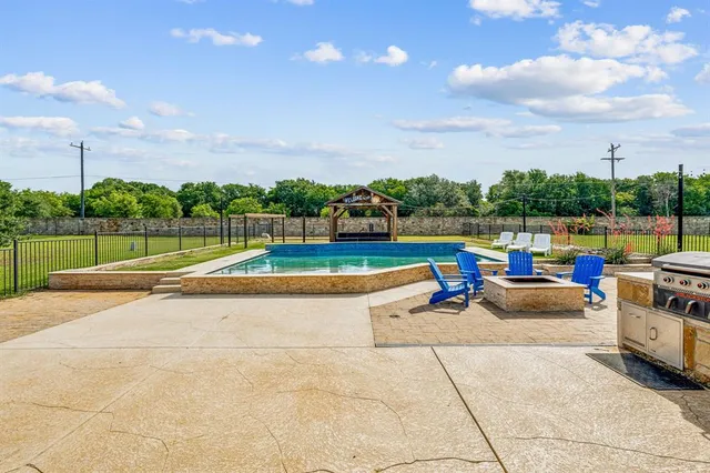 a view of swimming pool with seating space and barbeque oven in the back