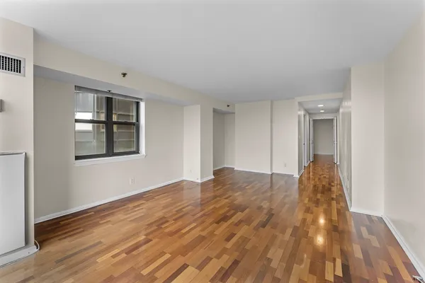 a view of empty room with wooden floor and fan