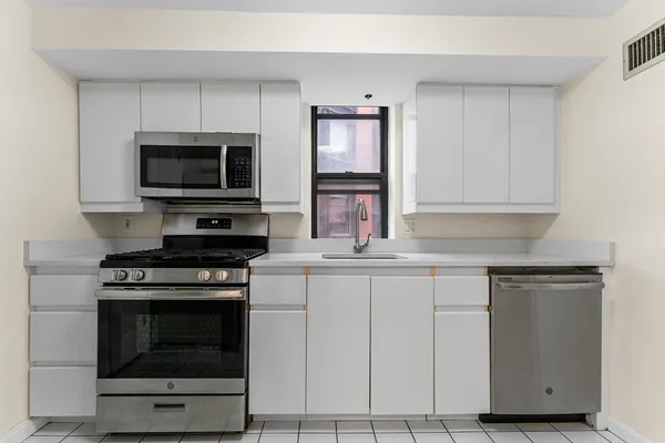 a kitchen with cabinets stainless steel appliances and wooden floor