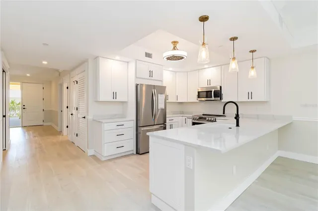 a kitchen with stainless steel appliances a refrigerator sink and white cabinets