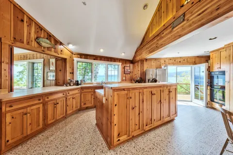 a large kitchen with stainless steel appliances granite countertop a large window a counter space and wooden floor