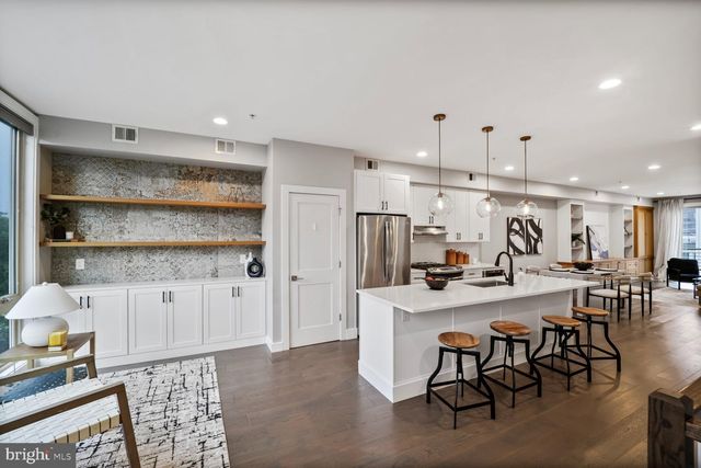 a kitchen with stainless steel appliances kitchen island granite countertop a table chairs and a refrigerator