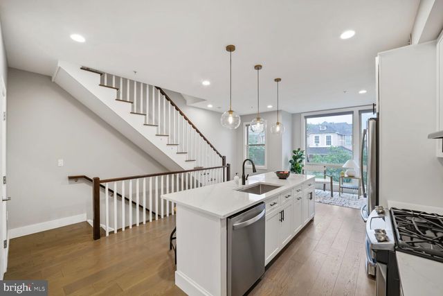 a large white kitchen with a large window a island a stove and a wooden floor