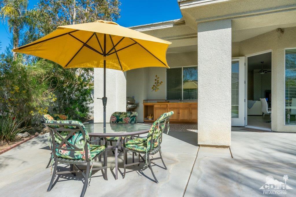 19 Napoleon Road Rancho Mirage, CA 92270 - Photo 35 of 41 a patio with a table and chairs under an umbrella