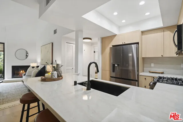 a large kitchen with stainless steel appliances a large counter top a stove and a refrigerator