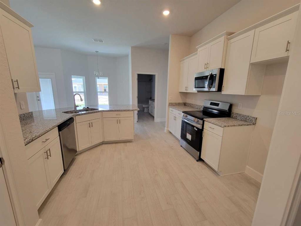 4626 Southwest 103rd Street Road Ocala, FL 34476 - Photo 11 of 29 a large kitchen with cabinets a sink a window and stainless steel appliances