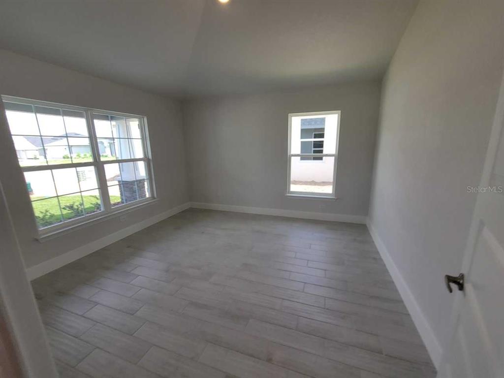 4626 Southwest 103rd Street Road Ocala, FL 34476 - Photo 6 of 29 an empty room with wooden floor and windows