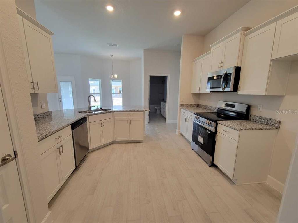 4626 Southwest 103rd Street Road Ocala, FL 34476 - Photo 9 of 29 a kitchen with granite countertop a sink a stove and cabinets