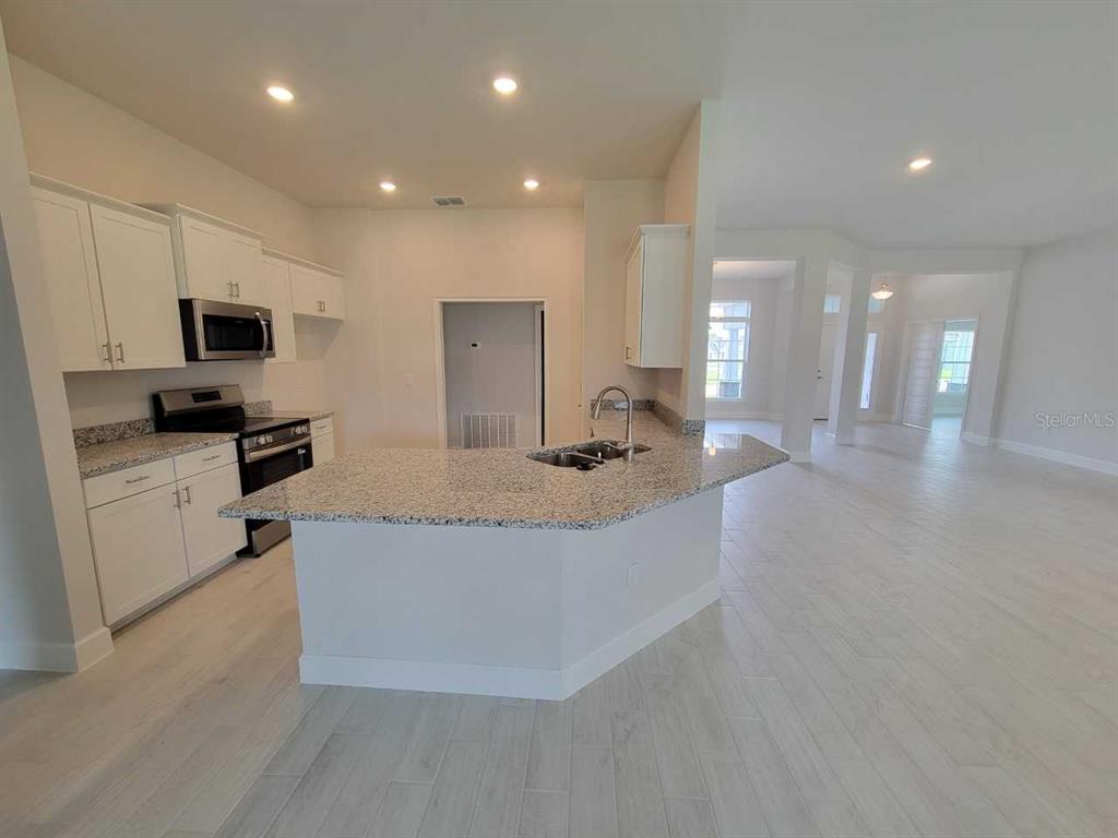 4626 Southwest 103rd Street Road Ocala, FL 34476 - Photo 10 of 29 a large kitchen with stainless steel appliances a large counter top a stove a sink a refrigerator and a refrigerator