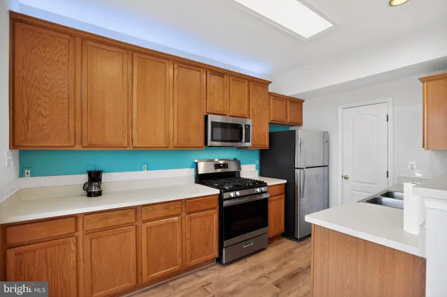 a kitchen with stainless steel appliances a stove a sink a refrigerator a microwave and cabinets