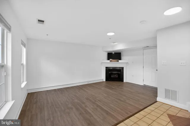 an empty room with wooden floor fireplace and windows