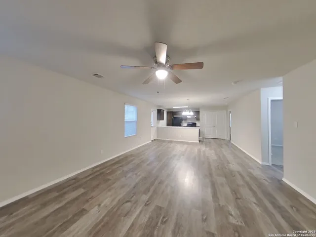 a view of empty room with wooden floor and ceiling fan