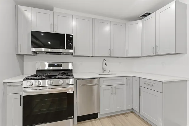 a kitchen with white cabinets and stainless steel appliances