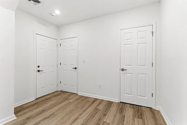 a view of an empty room with closet and wooden floor