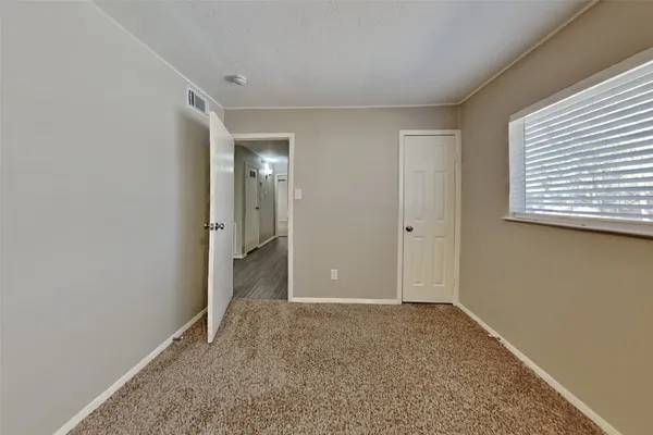 a view of an empty room with closet and entryway
