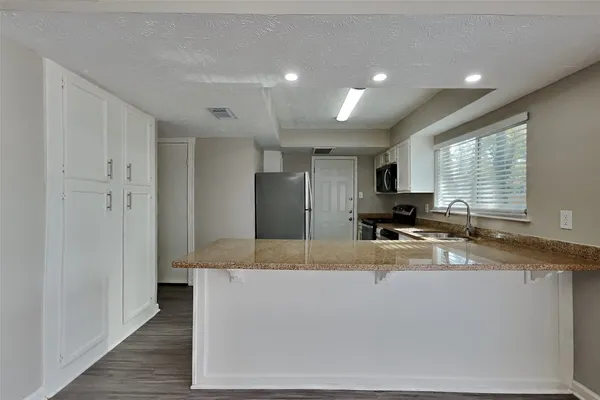 a large kitchen with stainless steel appliances granite countertop a sink a stove and a refrigerator