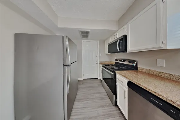 a kitchen with stainless steel appliances granite countertop a refrigerator and a stove top oven
