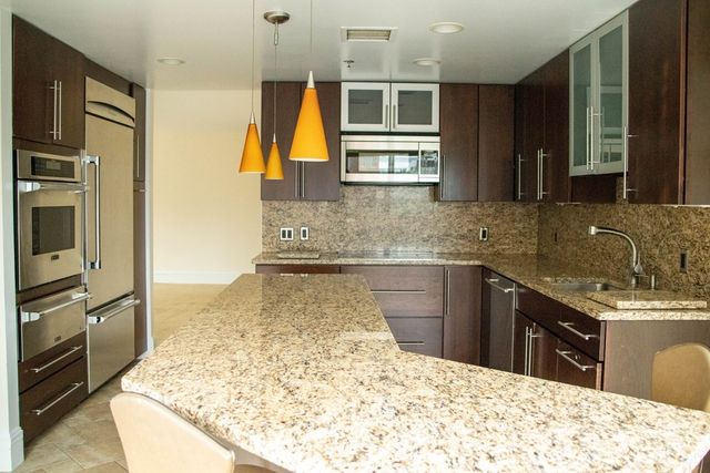 a kitchen with kitchen island granite countertop a sink stove and refrigerator