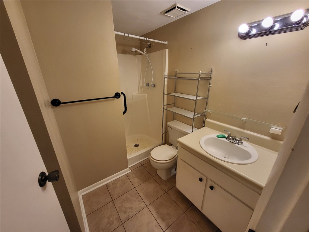 150 Ligon Street, Unit 1001 Clemson, SC 29631 - Photo 21 of 29 Functional bathroom featuring a shower, toilet, and vanity with built-in storage, all illuminated by bright overhead lighting.