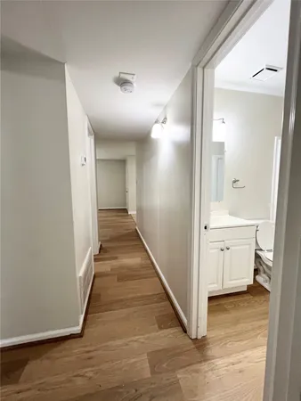 a view of a hallway with white walls and wooden floor