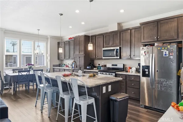 a kitchen with stainless steel appliances kitchen island granite countertop a refrigerator a stove top oven a sink and dishwasher