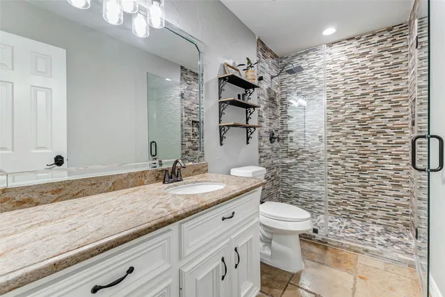 a bathroom with a granite countertop sink a toilet and a mirror