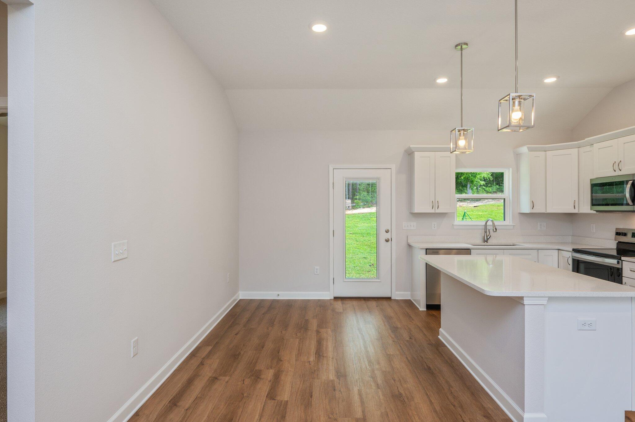 3929 Poverty Creek Road Crestview, FL 32539 - Photo 10 of 37 a kitchen with a wooden floor a window cabinets and stainless steel appliances