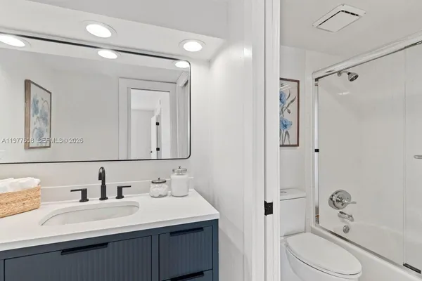 a bathroom with a sink vanity granite toilet and shower