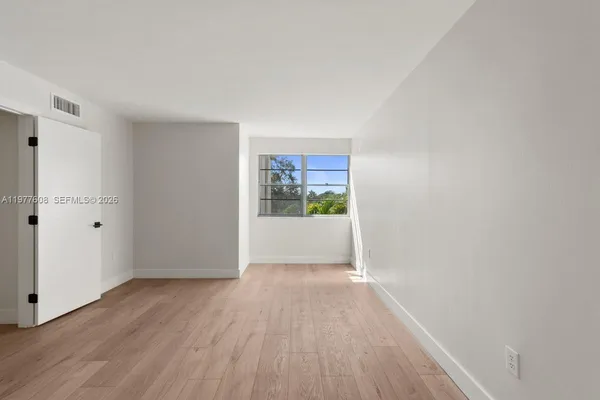 a view of a big room with wooden floor and windows