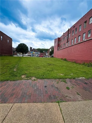 a view of a street with a big yard and large trees