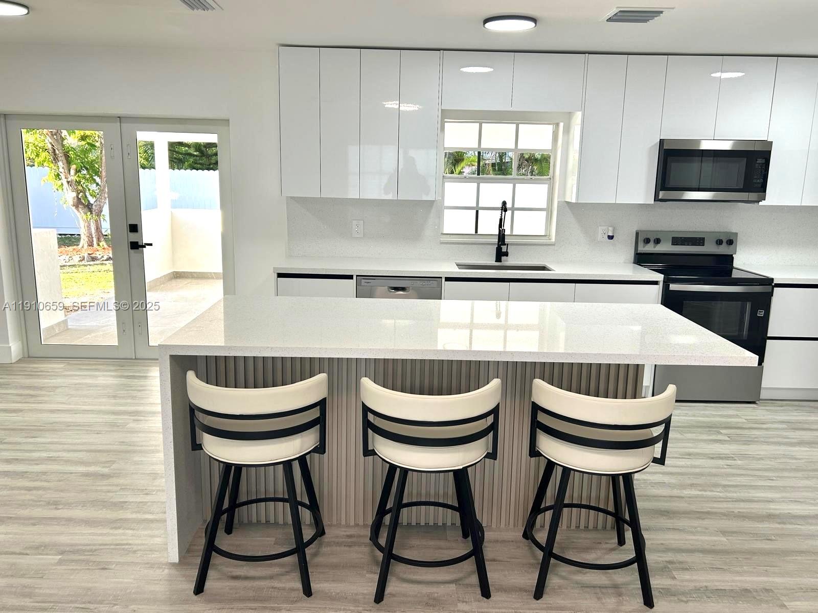 14211 Southwest 286th Street Homestead, FL 33033 - Photo 13 of 38 a kitchen with stainless steel appliances a kitchen island a stove a table and chairs