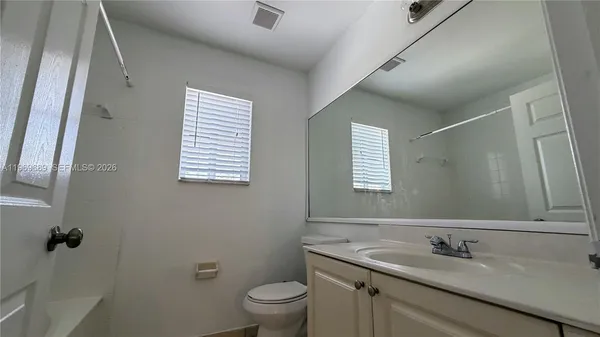 a bathroom with a granite countertop sink toilet and mirror