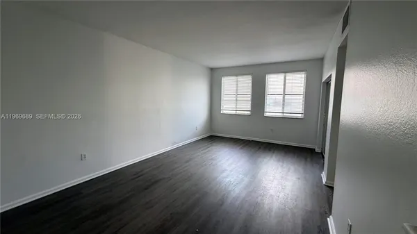 an empty room with wooden floor and windows