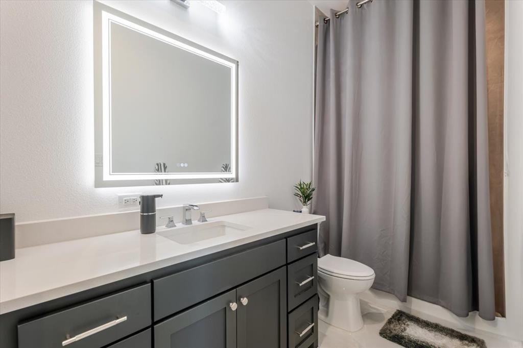 7381 Mesquite Ridge Sanger, TX 76266 - Photo 23 of 40 a bathroom with a sink a toilet a mirror and shower curtain